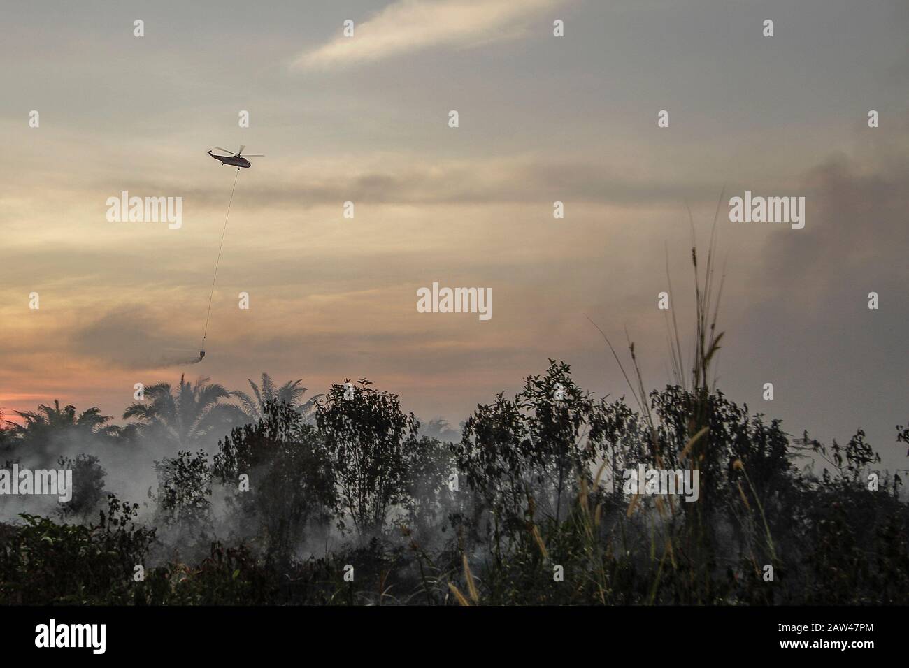 A water bombing helicopters try to extinguish land fires in Rimbo Panjang Village, Kampar Regency, Riau, October 6, 2019. Stock Photo