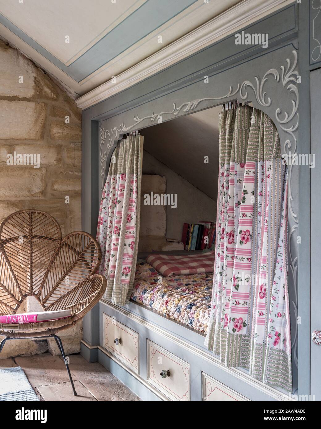 Cane chair by recessed bed in vintage style bedroom Stock Photo Alamy