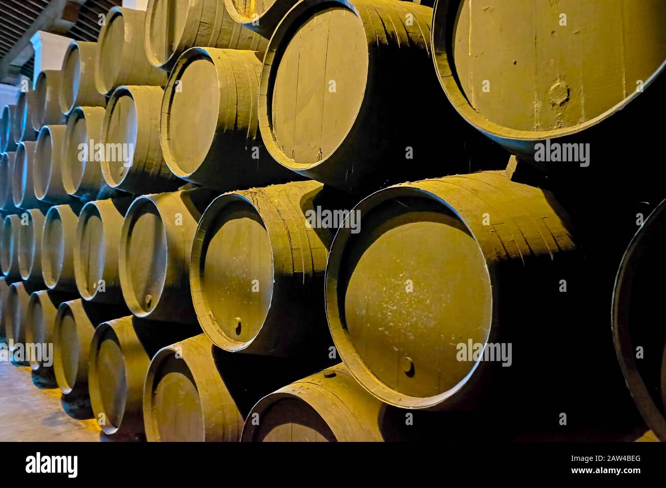 Explore solera wine ageing process and watch the row of stacked black sherry casks on the ground of old winery, Jerez, Spain Stock Photo