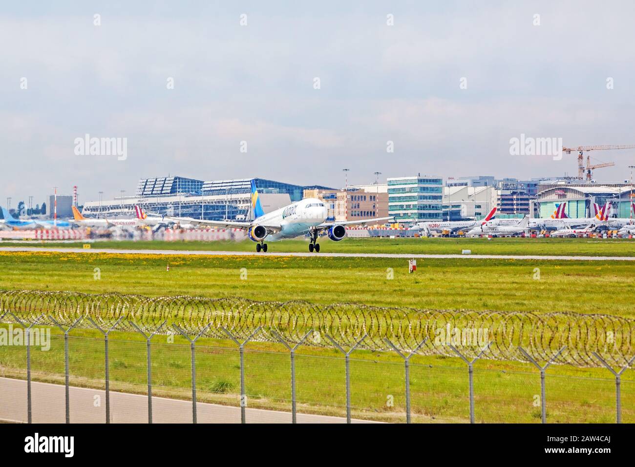Stuttgart, Germany - April 29, 2017: Airbus airplane A320 from Condor at takeoff from runway - airport Stuttgart terminal in background - green meadow Stock Photo