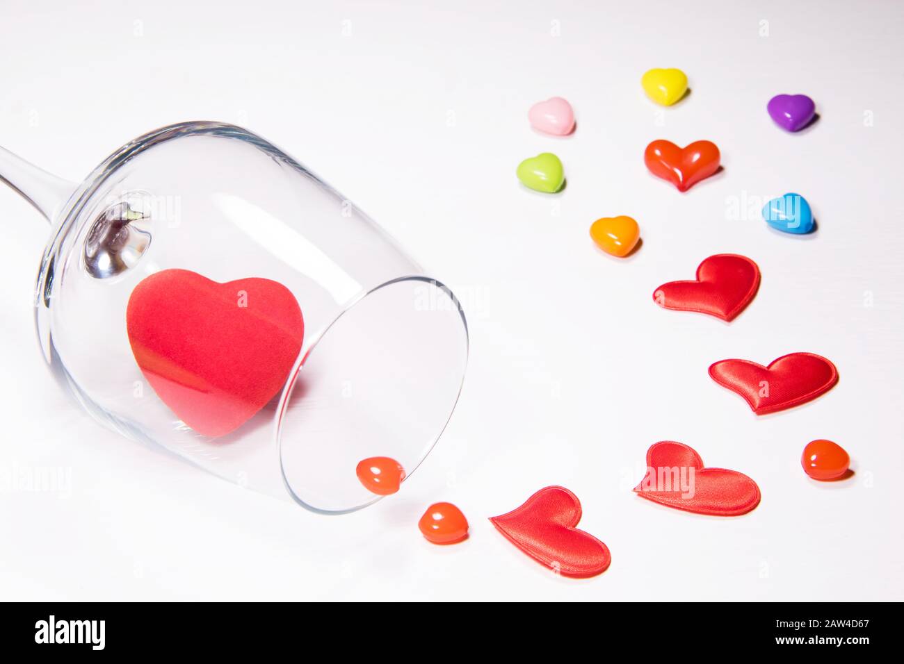 From the inverted glass drop out colorful hearts on white background Stock Photo