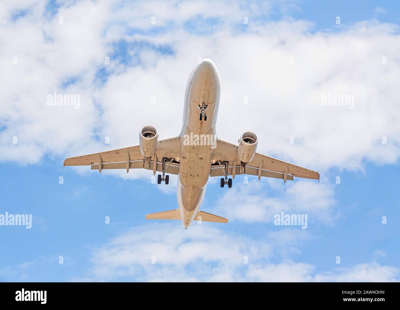 Flying airplane from below - landing / departure - blue sky with clouds Stock Photo