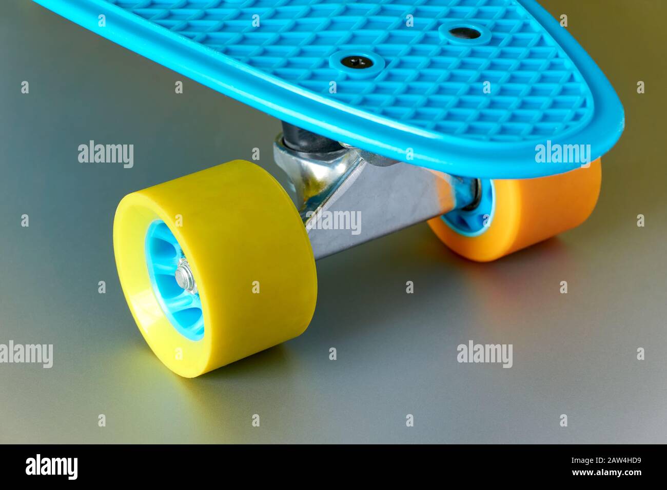 Detail of blue plastic mini cruiser penny board or skate board with yellow  and orange wheels and metal attachment on shiny metal grey background Stock  Photo - Alamy