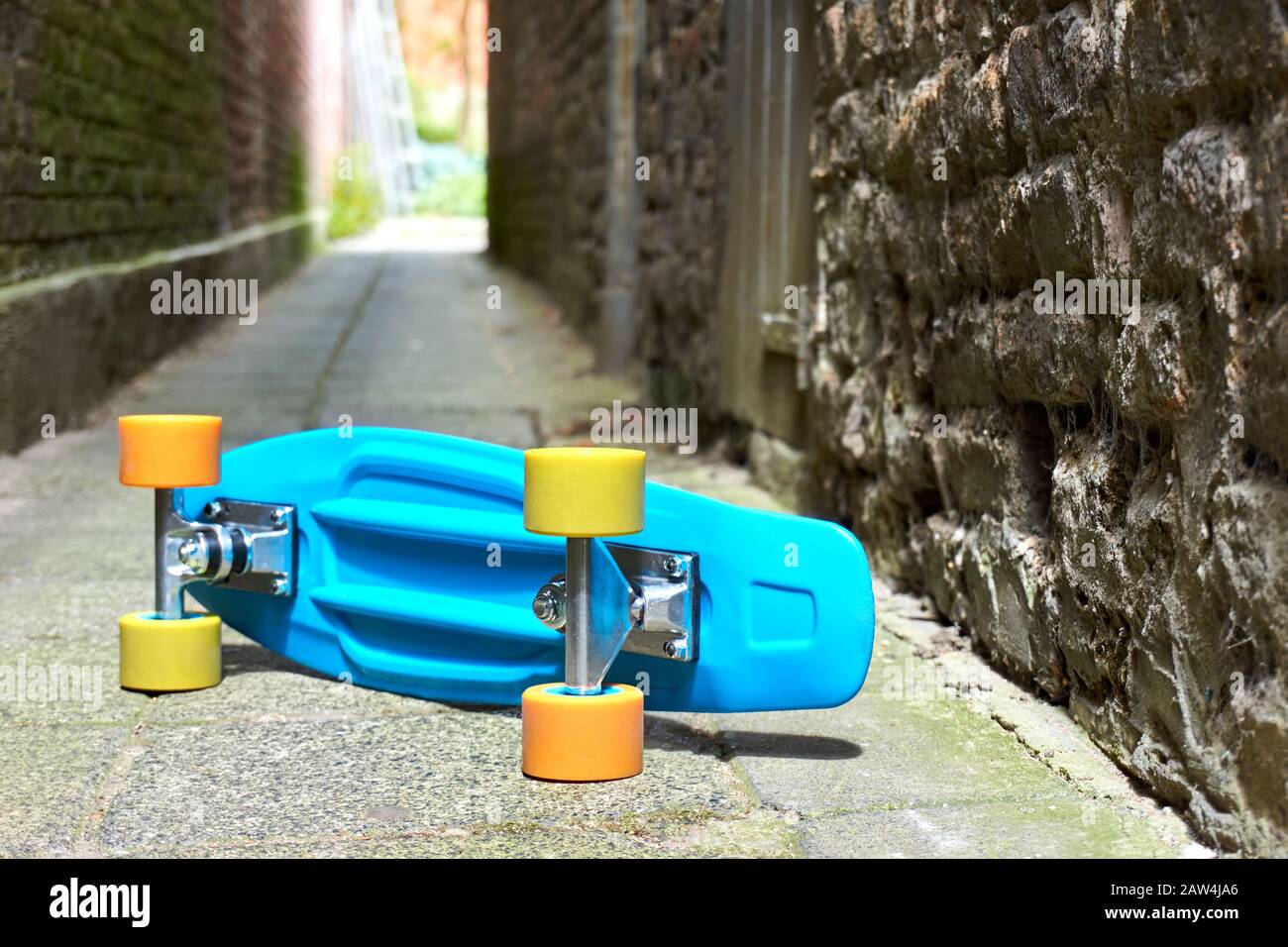 Blue plastic mini cruiser penny board or skate board with yellow and orange wheels laying on its