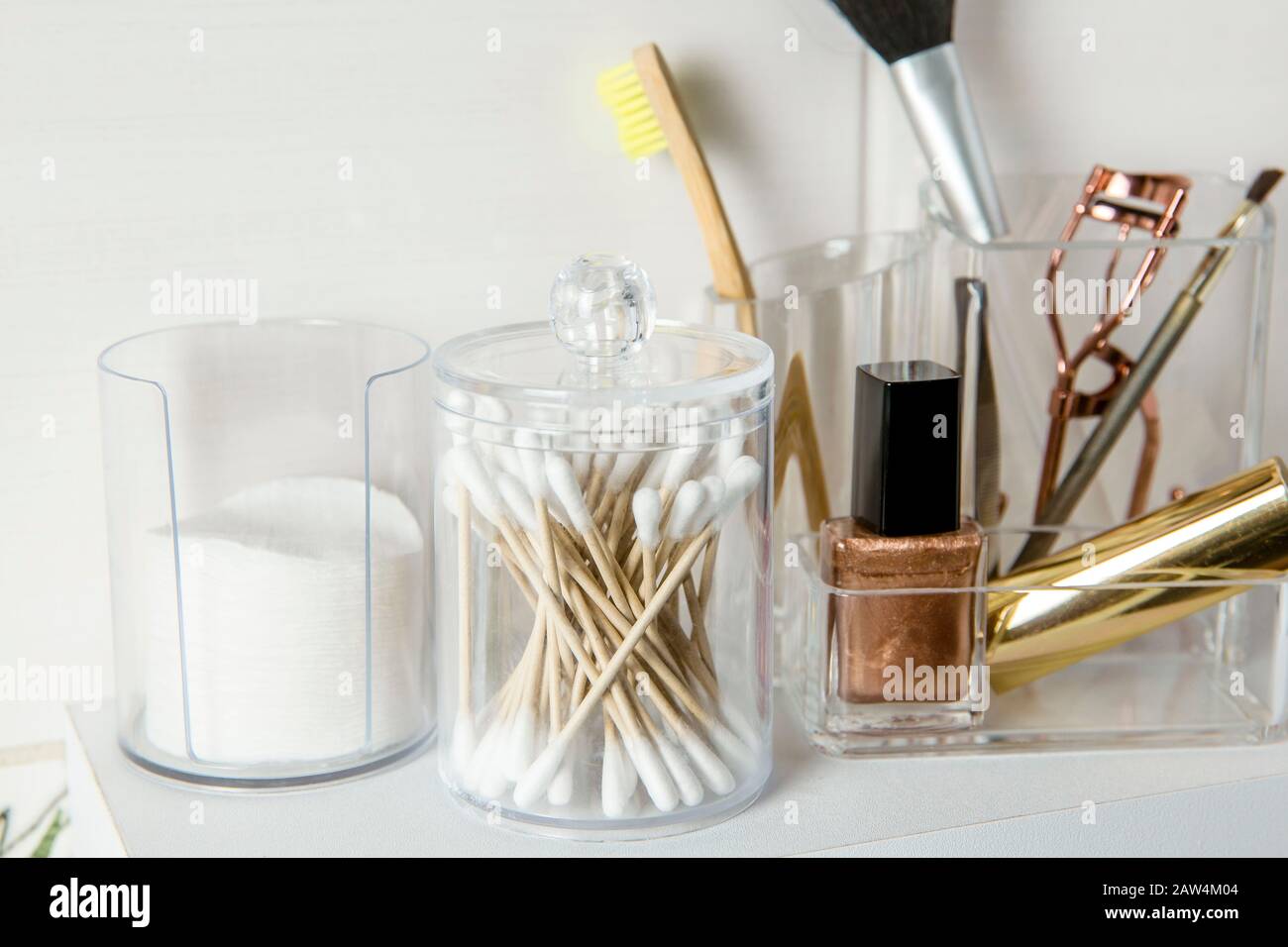 Make up products organizing concept. Beauty products in organizer container box on tidy way on minimalist shelf. Cotton pads stacked, Q-tips. Stock Photo