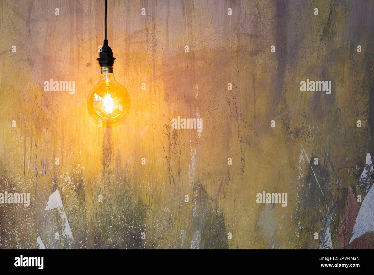 Warm glow from a hanging light illuminating an abstract wall painting