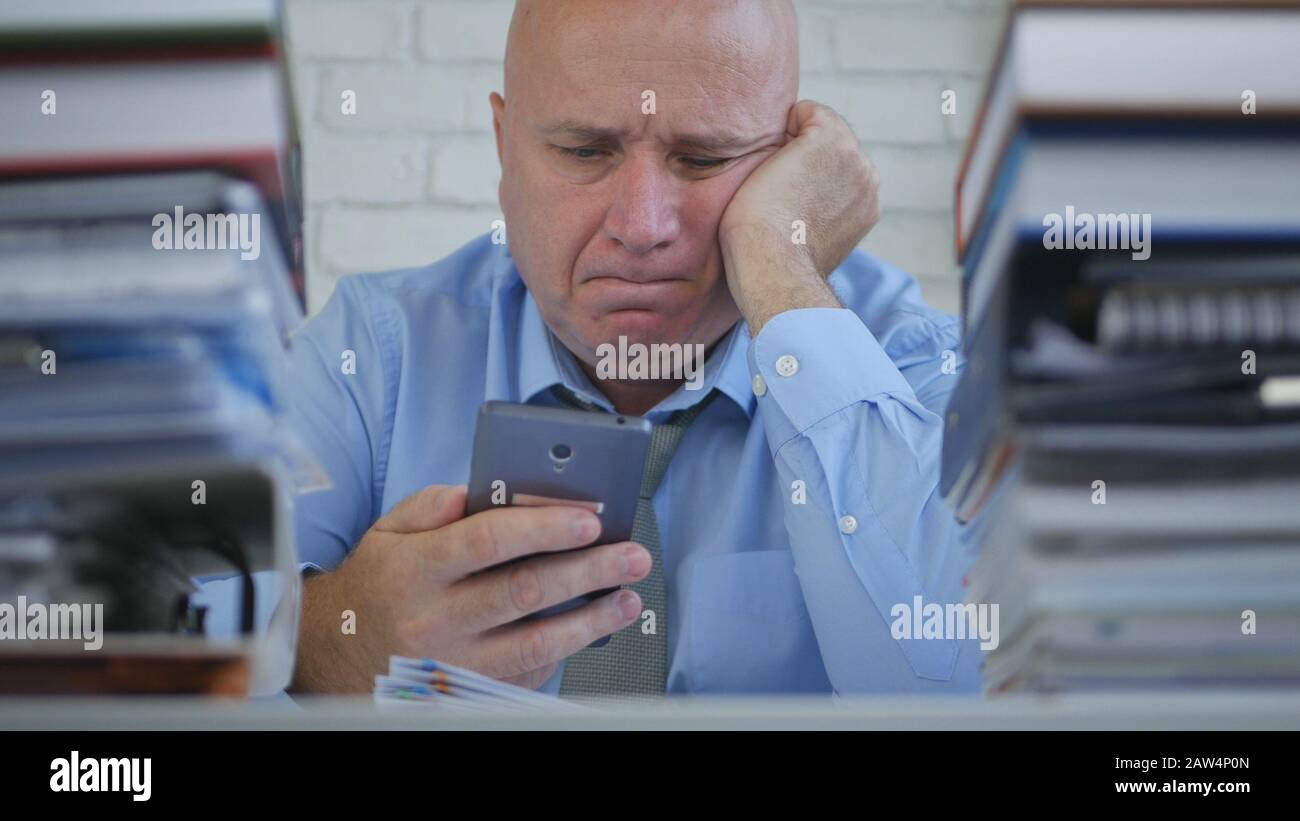 Tired Overworked and Upset Businessman Looking to Mobile Phone Message With a Disappointed Attitude Stock Photo