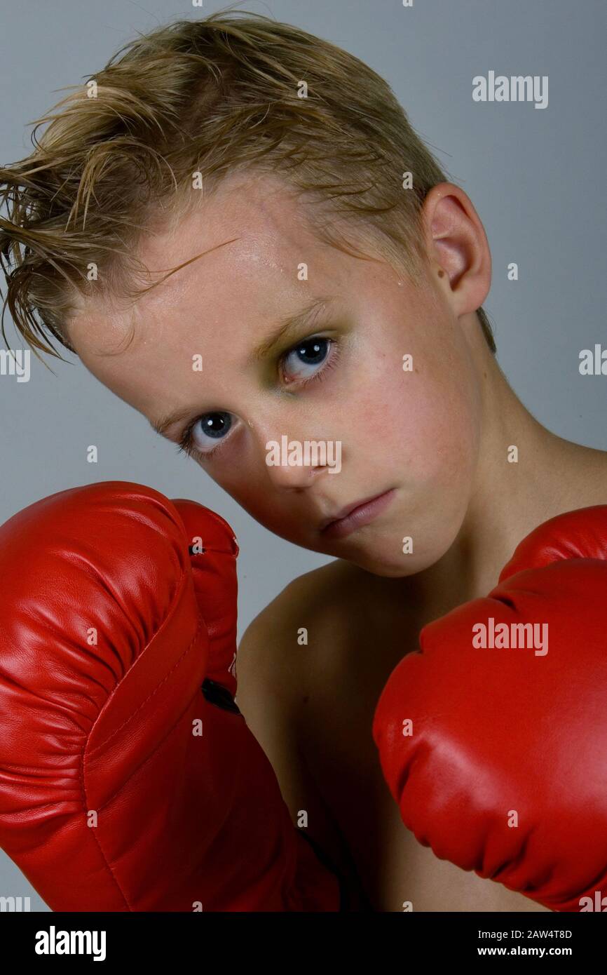 A young boy boxer with a back eye puts up his defense with his red boxing gloves on. Stock Photo