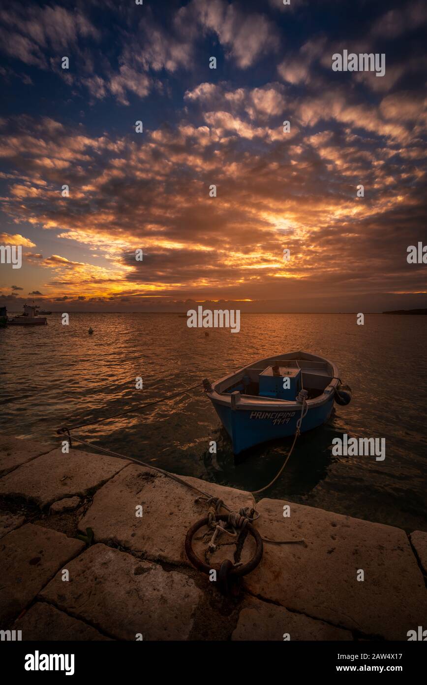 Sunset in a little port of Salento Porto Cesareo with a fisher boat and dramatic sky Stock Photo