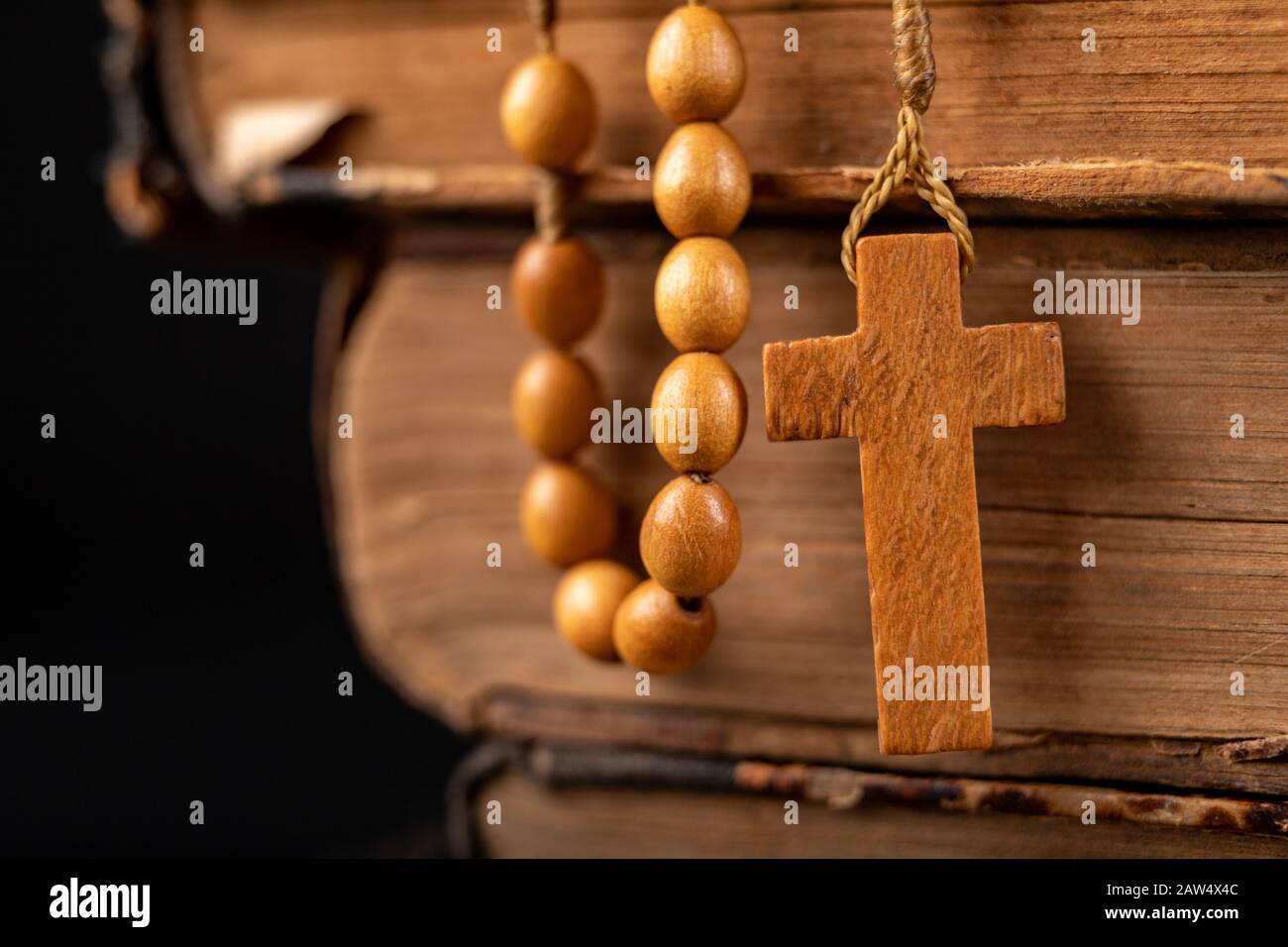 Wooden rosary arranged on an old book. Accessories for prayer in a  Christian church. Dark background Stock Photo - Alamy