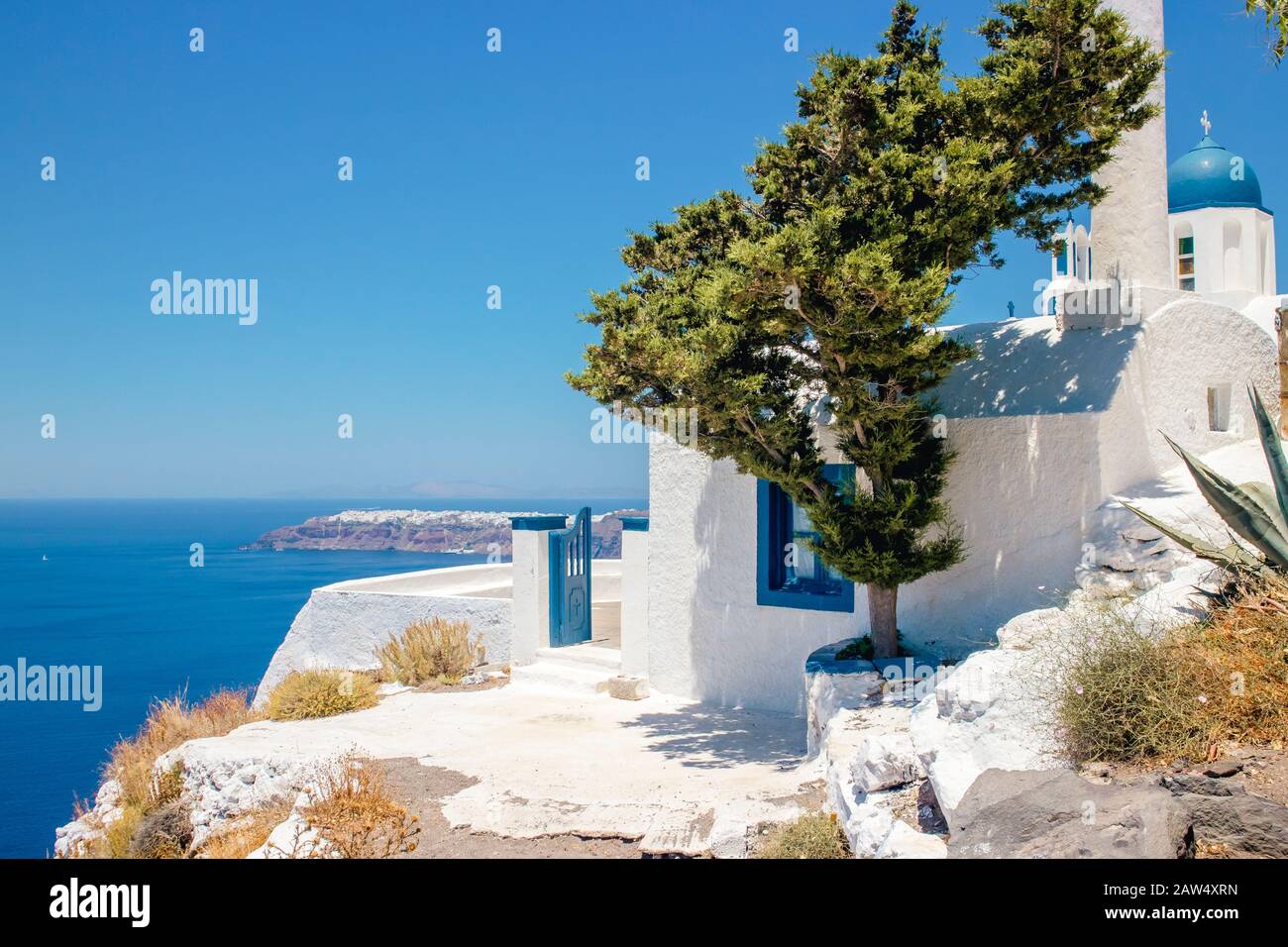 Selective focus on blue dome church (Theoskepasti) on the side of the Skaros Rock on volcanic island of Santorini in Greece, Europe. City of Oia on ca Stock Photo