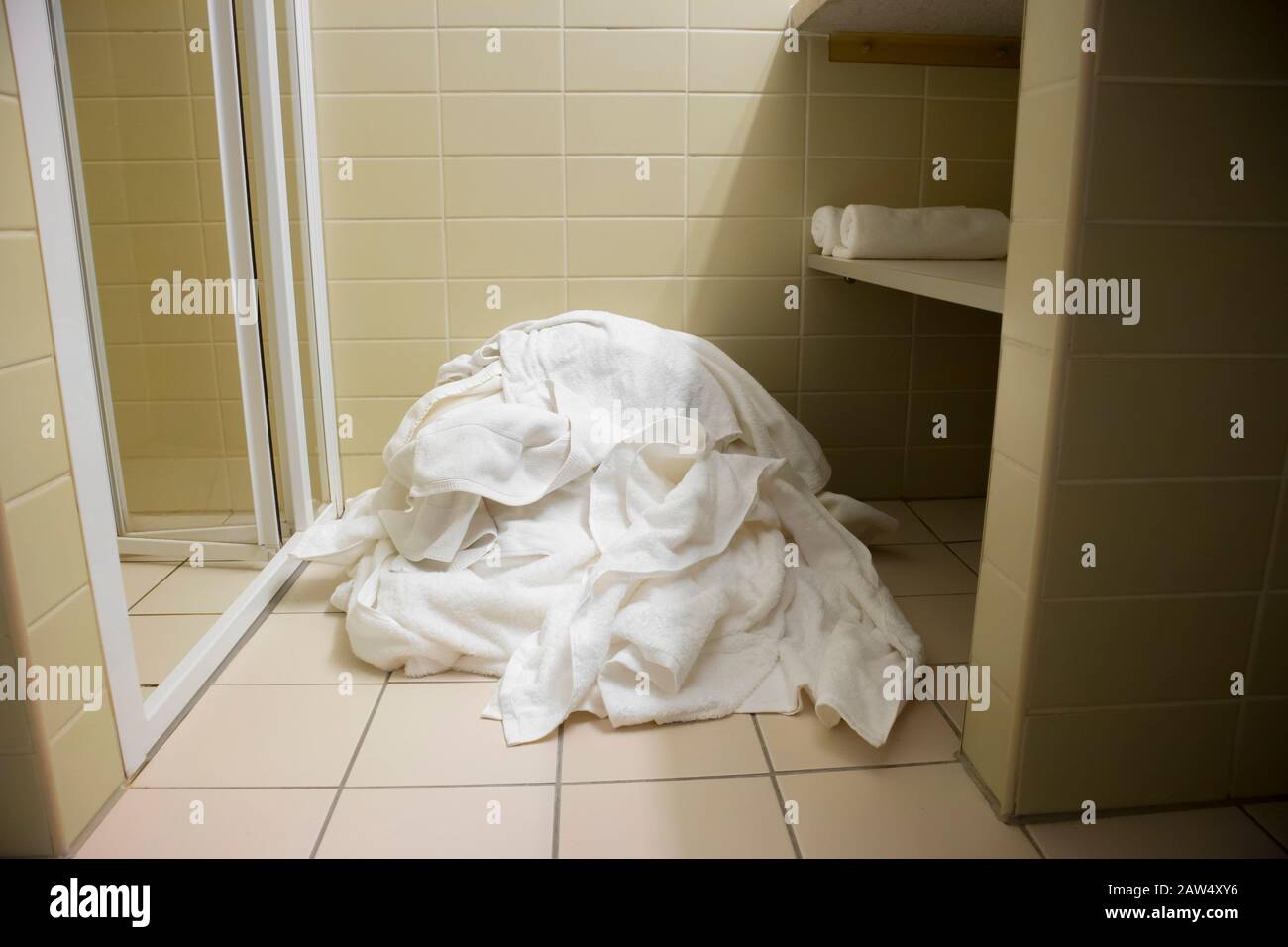 Pile of dirty used towels on the hotel bathroom floor. Housekeeping replace only the used towels on floor with clean ones. Saving water, soap, energy Stock Photo