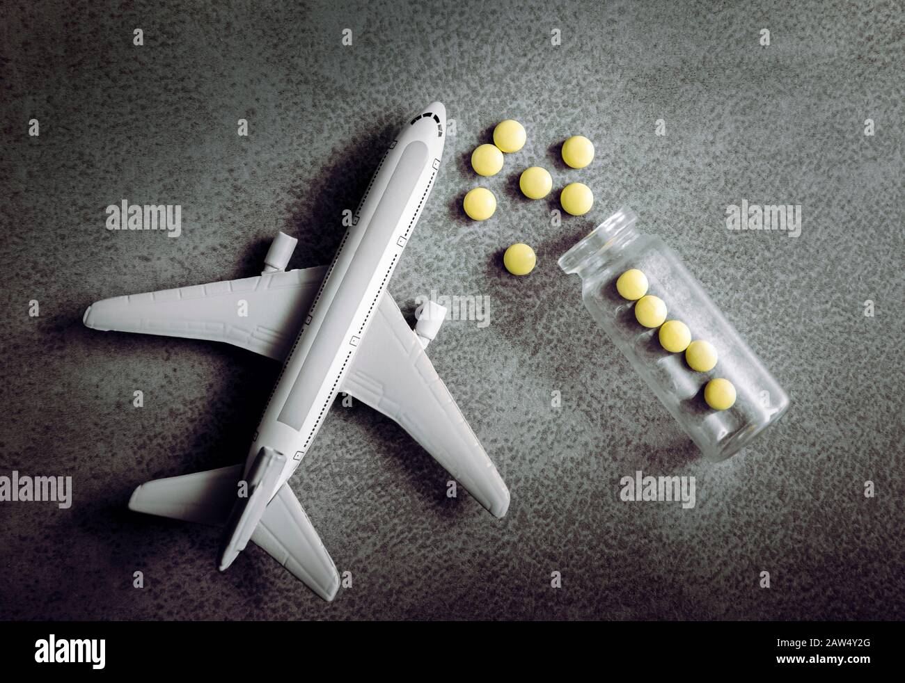 Plane figurine with pills spilled. Travel and medicine concept. Flat lay view with copy space on minimalist gray background. Stock Photo