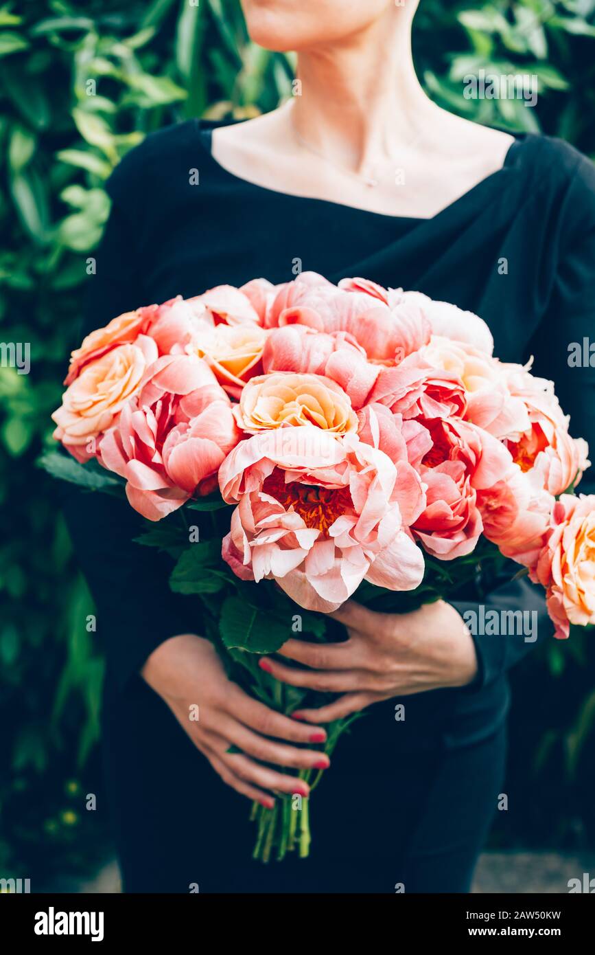 Woman in black dress is holding bunch of pink peonies and roses. Card ...