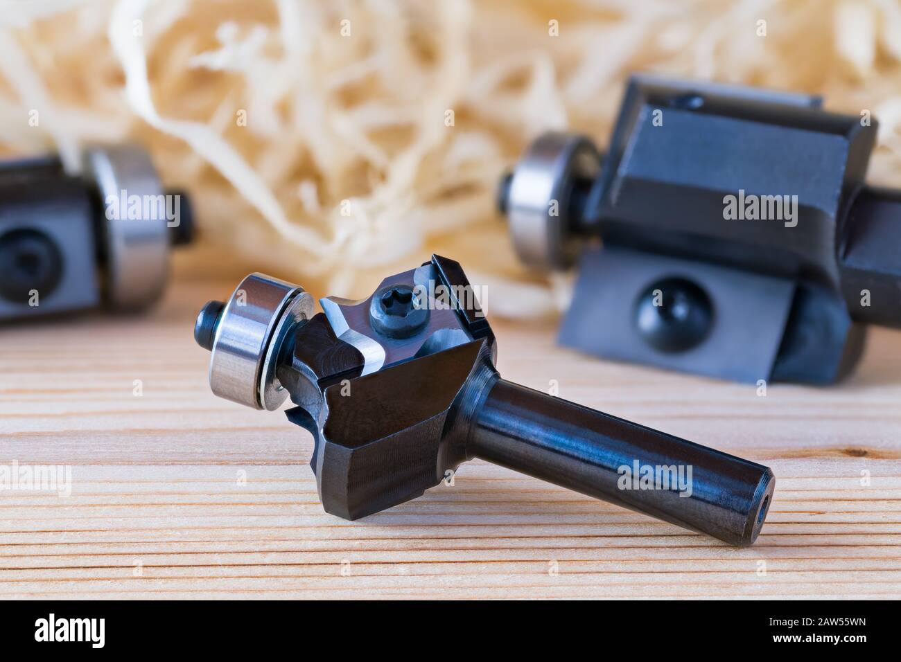 Trimming shank router cutters. Milling cutting tools on wood background. Shaping copying endmills with replaceable knives with 4 edges. Shavings pile. Stock Photo