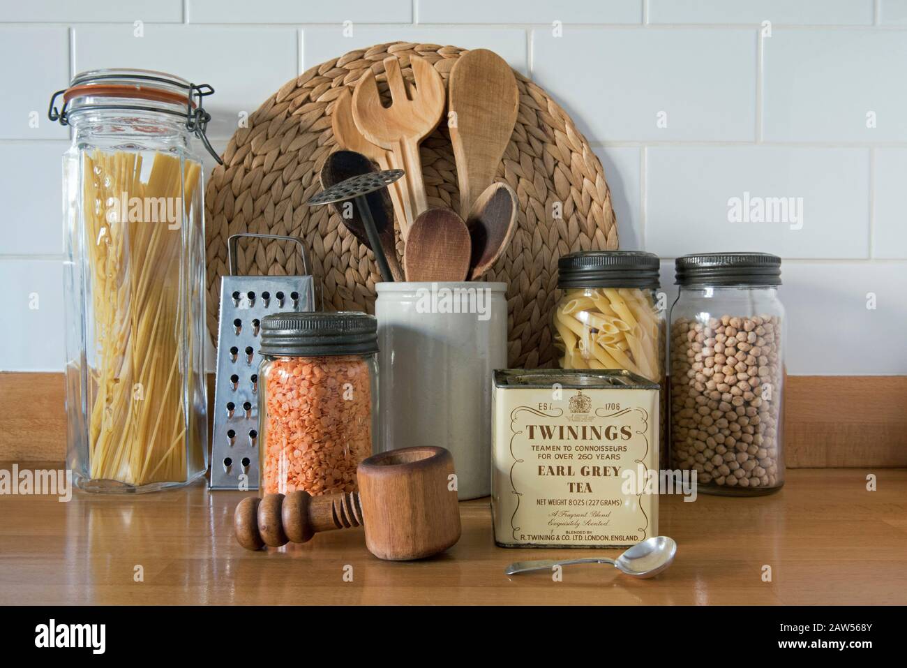 Eco friendly wooden kitchen utensils with vintage glass storage jars and tin of loose Earl Grey tea against white tiles in kitchen, zero waste concept Stock Photo