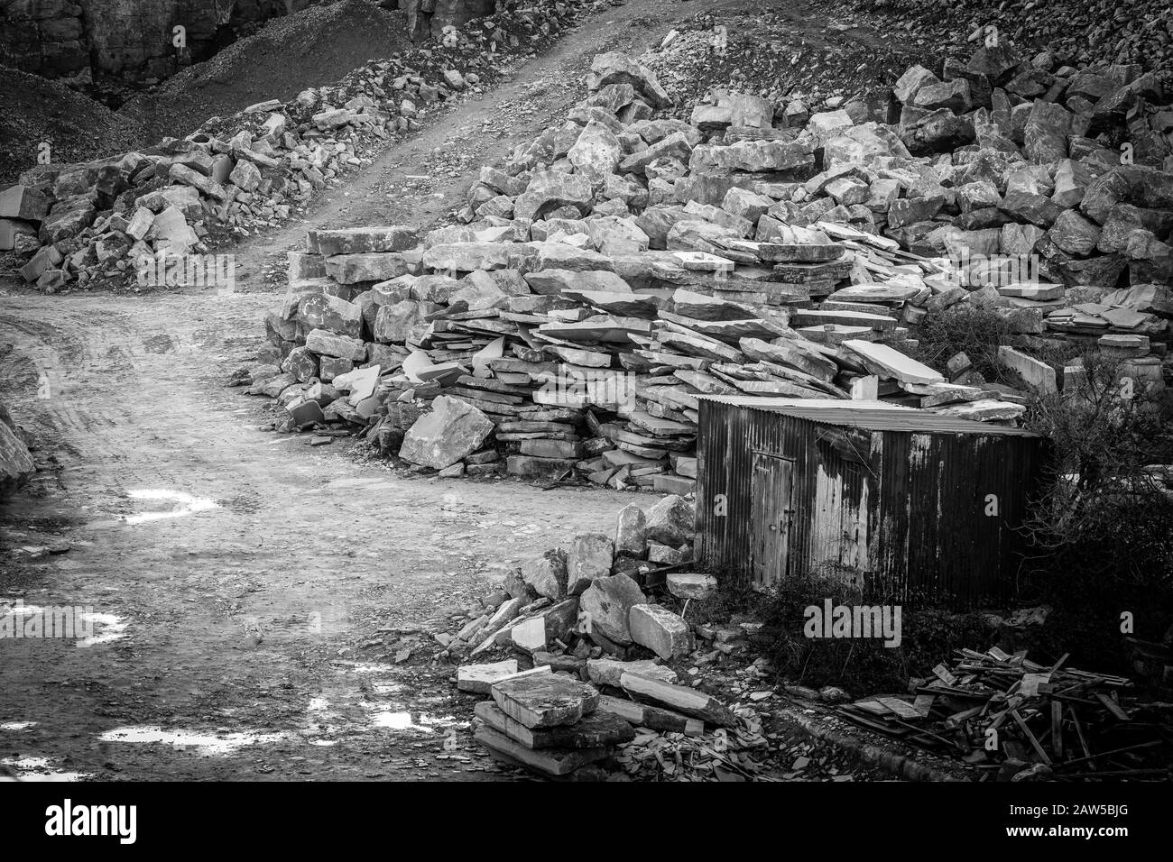 Road tracks and puddles in stone quarry with old tin shed Stock Photo