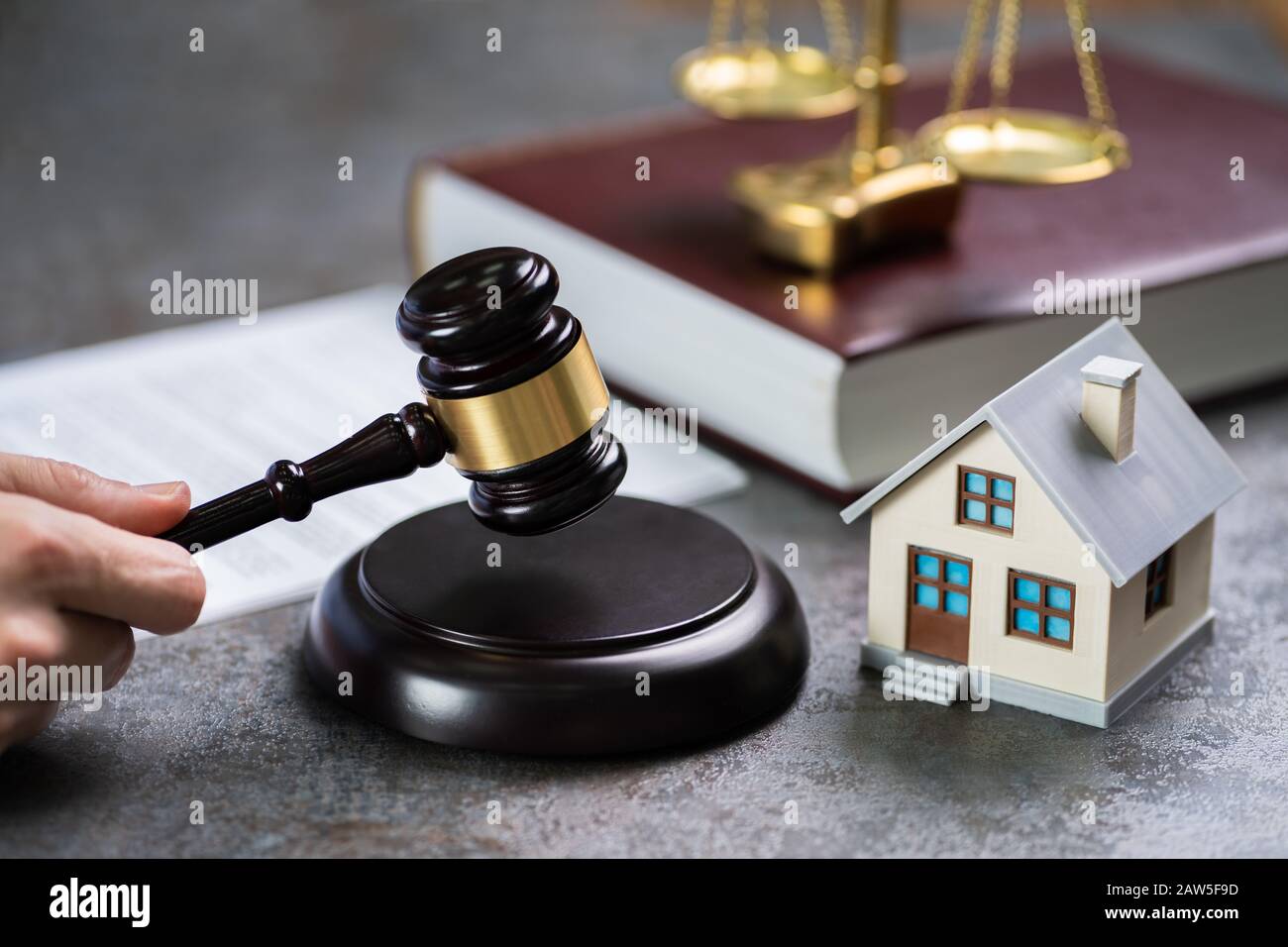 Close-up Of Judge With House Model Striking Mallet At Desk Stock Photo