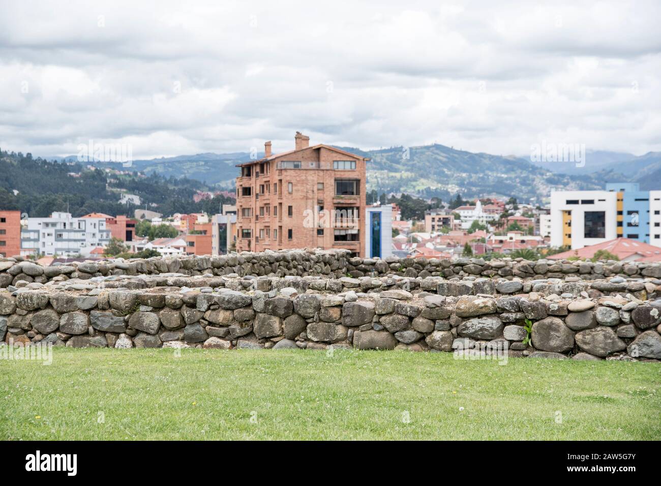 The modern city of Cuenca provides a backdrop to the Cañari-Incan ruins found at the Pumapungo Outdoor Archeology Museum. Stock Photo