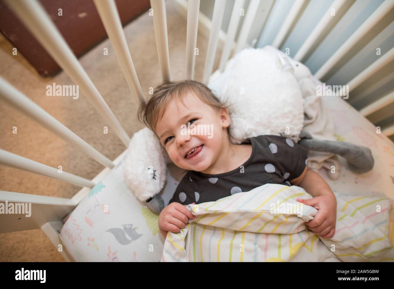 High angle of cute toddler girl smiling in her bed Stock Photo