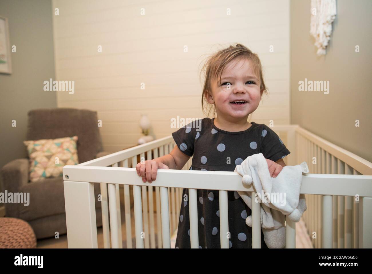 Portrait of cute toddler girl in her crib in bedroom. Stock Photo