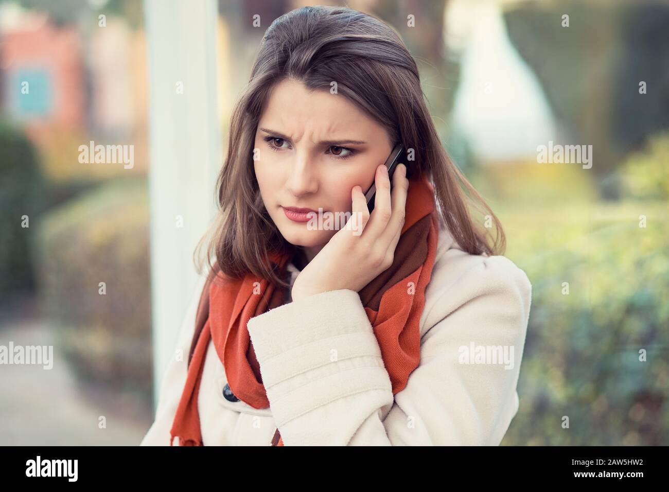 Unhappy customer. Closeup portrait headshot angry young woman talking on mobile phone looking frustrated serious girl student cityscape outdoor backgr Stock Photo