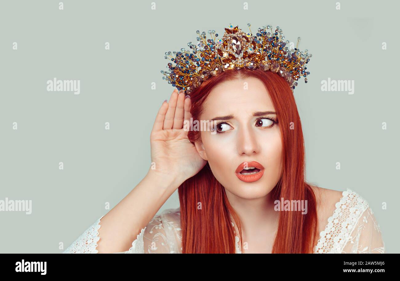 Eavesdropping bad news. Sad frustrated unhappy woman listening ear to bad news or having hearing impair hard of hearing pretty girl with crystal crown Stock Photo