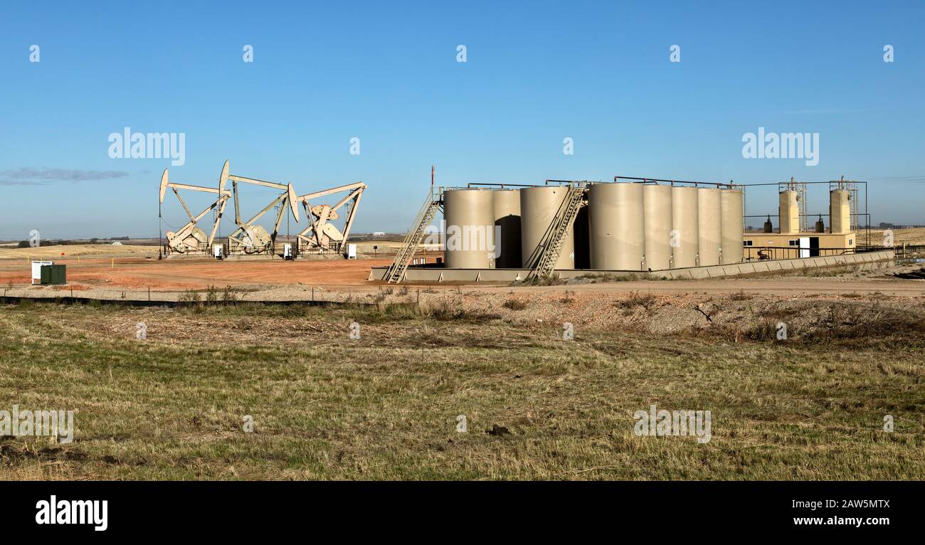 Nodding Donkey pumps operating, storage tanks, Williston Basin Bakken Shale Oil Formation Region. Stock Photo