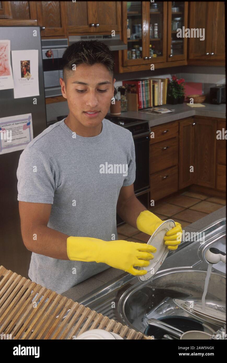 Austin, Texas Hispanic teenage boy wearing yellow rubber gloves while