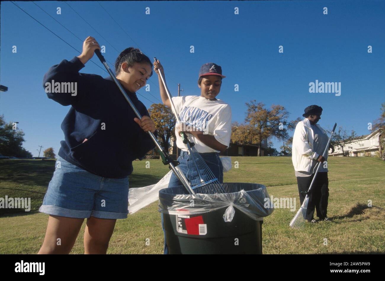 Teen volunteers help public housing resident with landscape clean-up at public housing project in Austin, Texas. Stock Photo