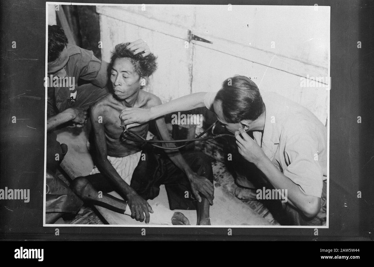 NICA hospital [an emaciated Indonesian man being examined by a doctor] Date: 1940-1945 Location: Indonesia Dutch East Indies Keywords: famine, natives, second world War nursing Stock Photo