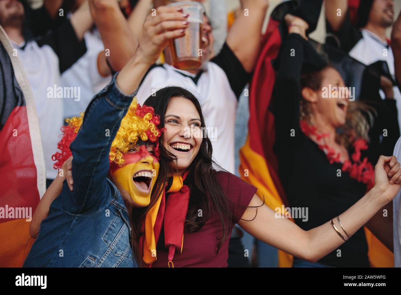 German supporters celebrating at stadium and drinking beer. Group of