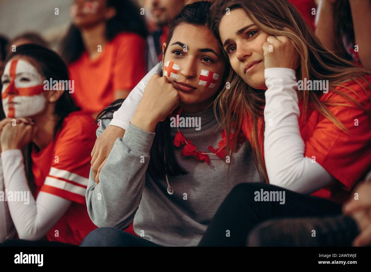 sports fans looking sad after losing a game. Upset English soccer fans in disappointment while watching a match in stadium. Stock Photo