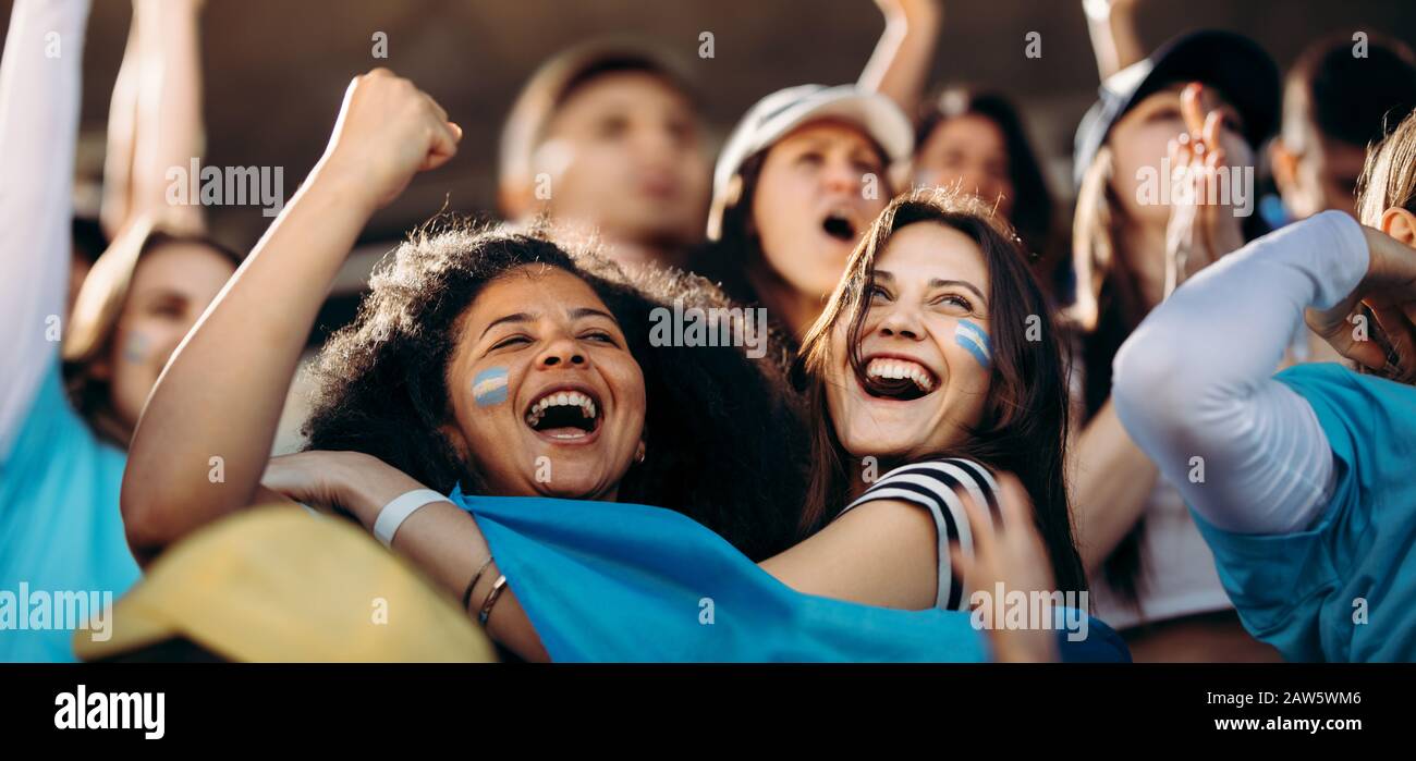 Female watching a sport event and cheering Argentina soccer team. Excited crowd of sports fans applauding and celebrating their team's victory. Stock Photo