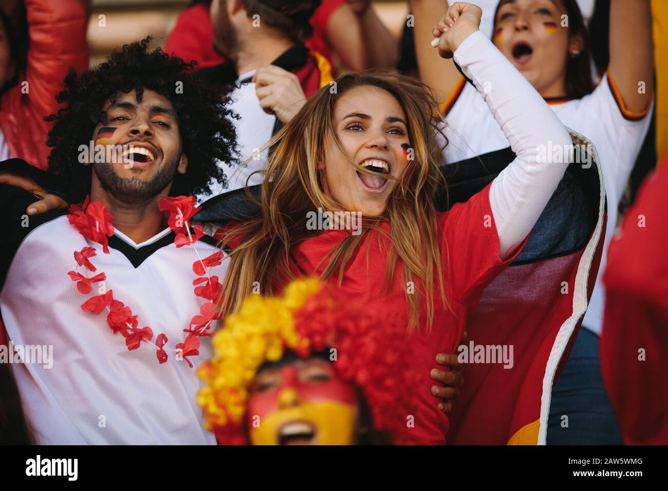 German spectators in stadium cheering their national team. People from Germany in fan zone jumping and chanting for their soccer team. Stock Photo