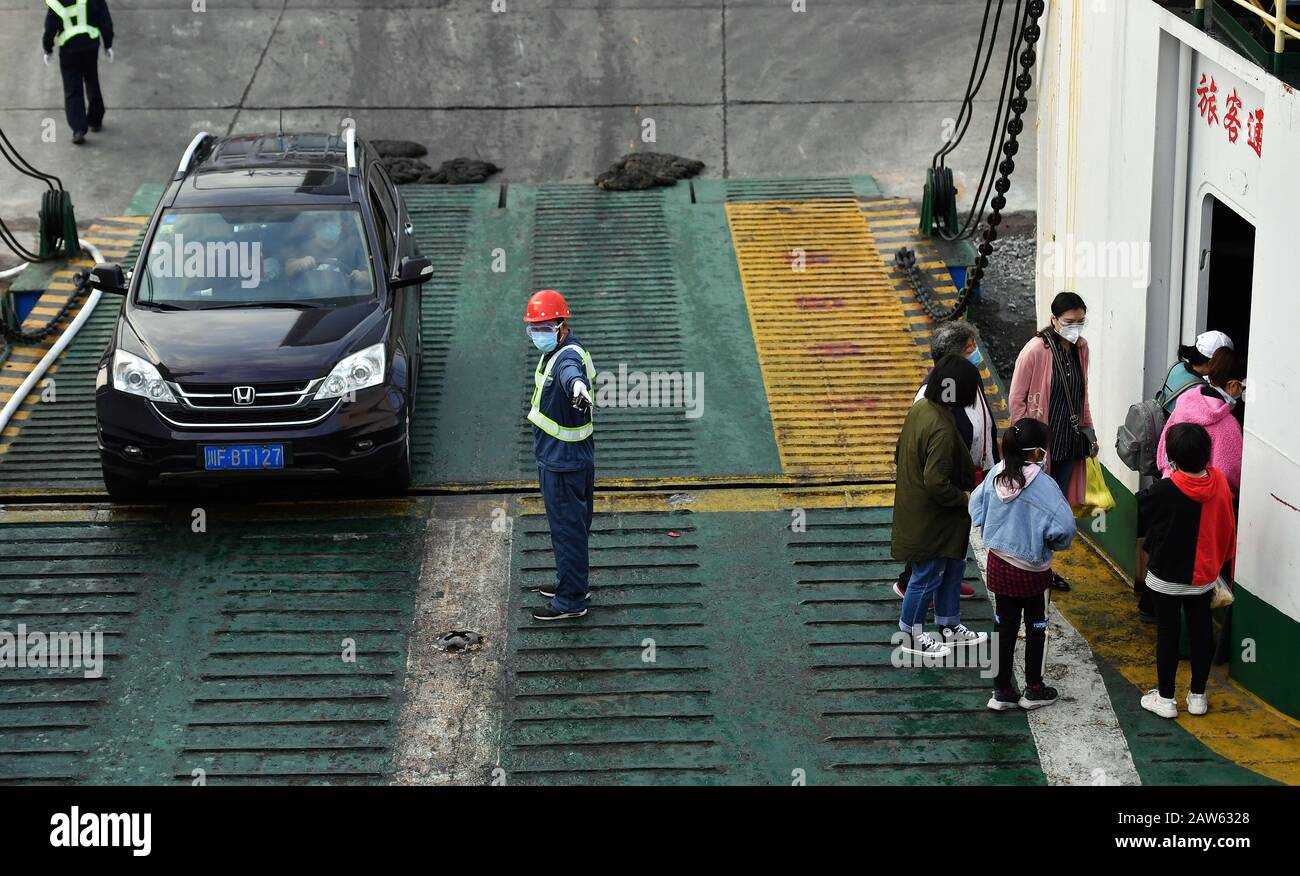 (200207) -- HAIKOU, Feb. 7, 2020 (Xinhua) -- A staff member guides people and cars boarding a ferry at Xiuyinggang Ferry Terminal in Haikou, south China's Hainan Province, Feb. 6, 2020. Qiongzhou Strait is a major passage into and out of Hainan Island. Since the start of the prevention and control of pneumonia caused by the novel coronavirus, Hainan and Guangdong have both moved the prevention and control threshold forward. Hainan has sent more than 160 joint anti-epidemic personnel from multiple departments to Zhanjiang of Guangdong Province, and set up four prevention and control points and Stock Photo