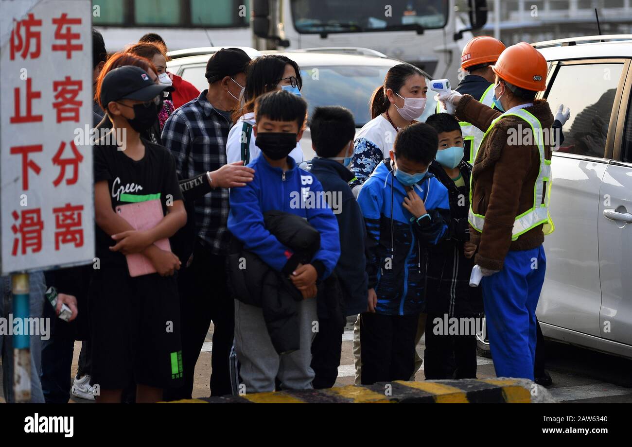(200207) -- HAIKOU, Feb. 7, 2020 (Xinhua) -- A staff member measures body temperature of passengers before their boarding at Xiuyinggang Ferry Terminal in Haikou, south China's Hainan Province, Feb. 6, 2020. Qiongzhou Strait is a major passage into and out of Hainan Island. Since the start of the prevention and control of pneumonia caused by the novel coronavirus, Hainan and Guangdong have both moved the prevention and control threshold forward. Hainan has sent more than 160 joint anti-epidemic personnel from multiple departments to Zhanjiang of Guangdong Province, and set up four prevention a Stock Photo