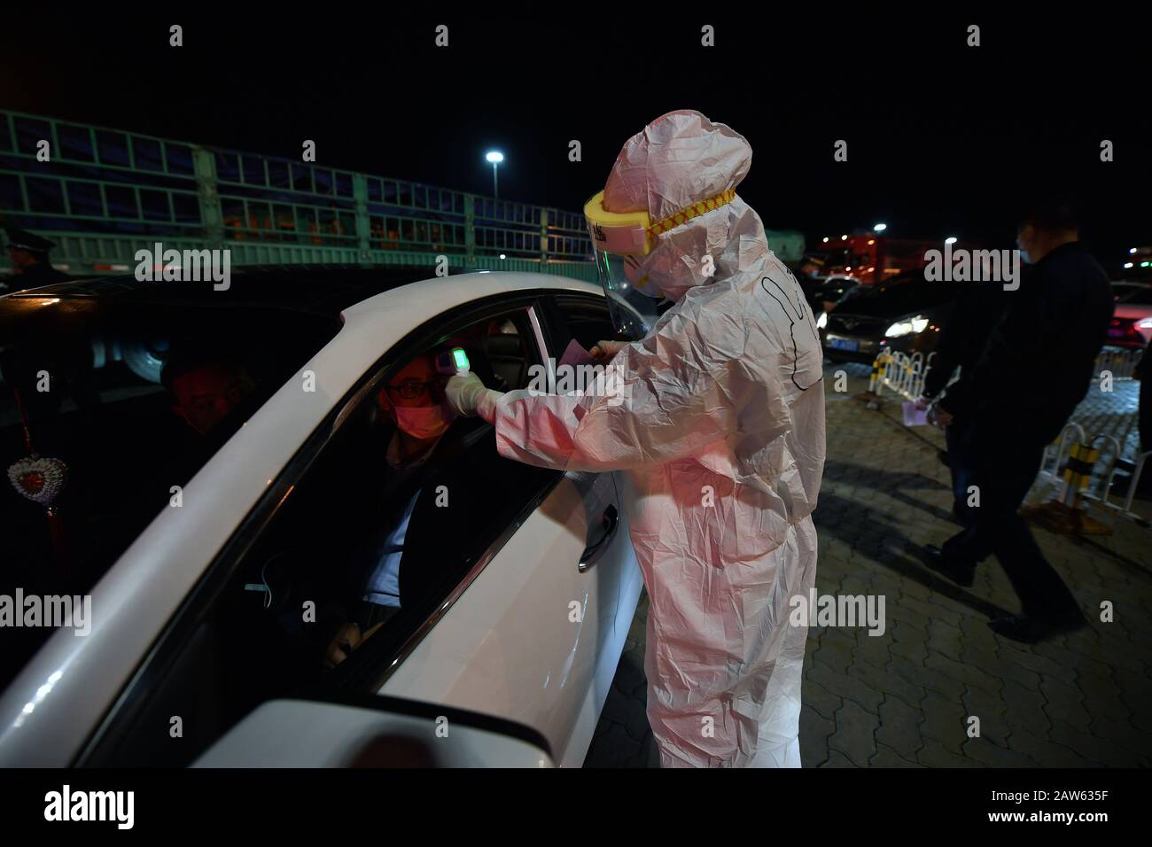 (200207) -- HAIKOU, Feb. 7, 2020 (Xinhua) -- A staff member measures body temperature of a passenger at Xinhaigang Ferry Terminal in Haikou, south China's Hainan province, Feb. 6, 2020. Qiongzhou Strait is a major passage into and out of Hainan Island. Since the start of the prevention and control of pneumonia caused by the novel coronavirus, Hainan and Guangdong have both moved the prevention and control threshold forward. Hainan has sent more than 160 joint anti-epidemic personnel from multiple departments to Zhanjiang of Guangdong Province, and set up four prevention and control points and Stock Photo