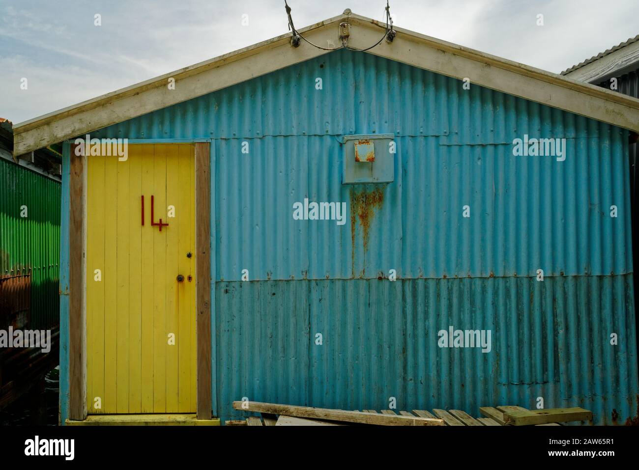 The number 14 in red on a rustic yellow shed door. Stock Photo