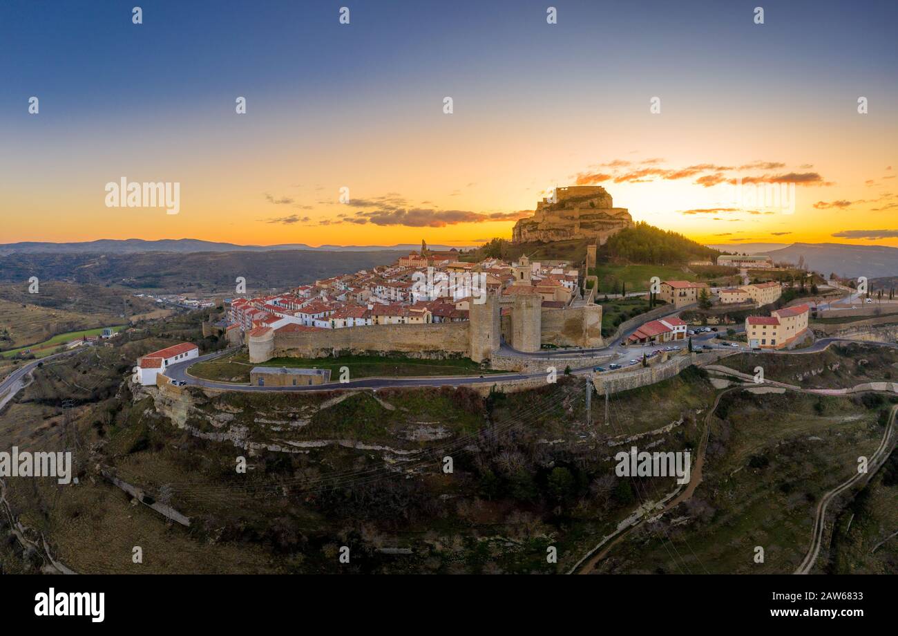 Aerial sunset view of Morella, medieval walled town with semi circular towers and gate houses crowed by a fortress on the rock in Spain Stock Photo