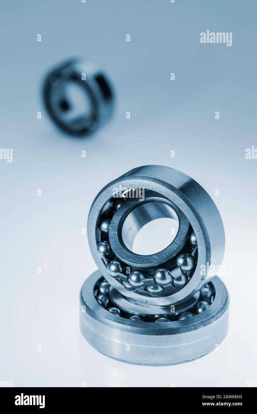 Close-up of two self-aligning self-aligning ball bearings with third out of focus ball bearings in vertical orientation isolated on white background w Stock Photo