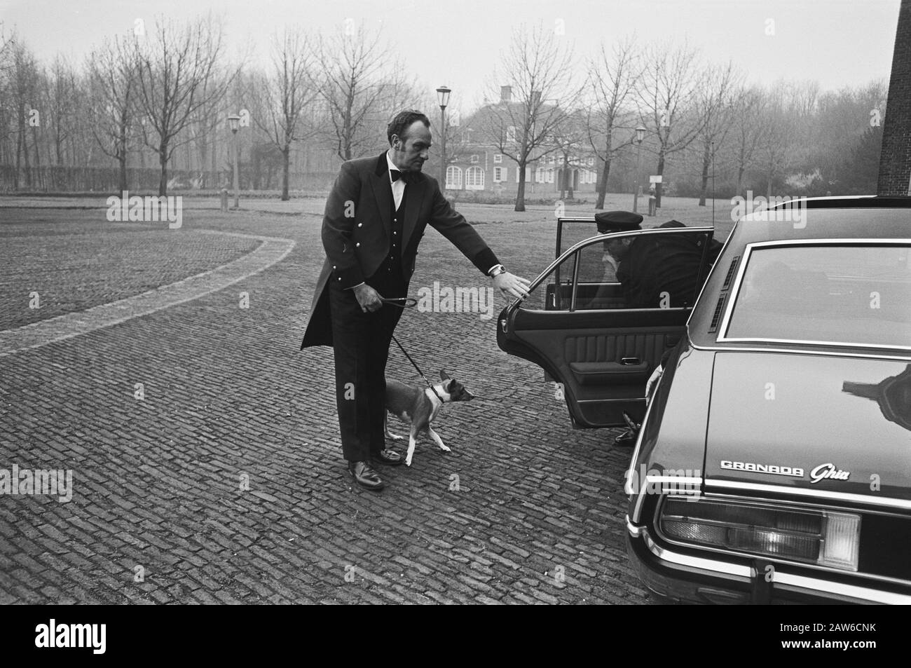 Reception of group leaders by Queen Juliana at Huis ten Bosch  Lackey with dog Sarah on arrival Queen Juliana and Prince Bernhard Date: March 24, 1977 Location: The Hague, Zuid-Holland Keywords: dogs, staff, government crises Person Name: Bernhard, prince (1911-2004), Sarah Stock Photo