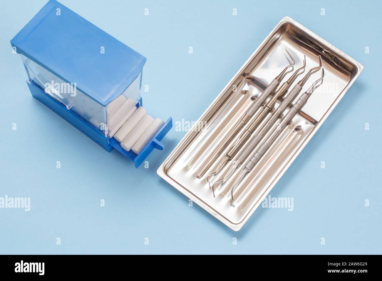 Set of composite filling instruments for dental treatment and plastic box with cotton tampons. Medical tools in stainless steel tray. Stock Photo