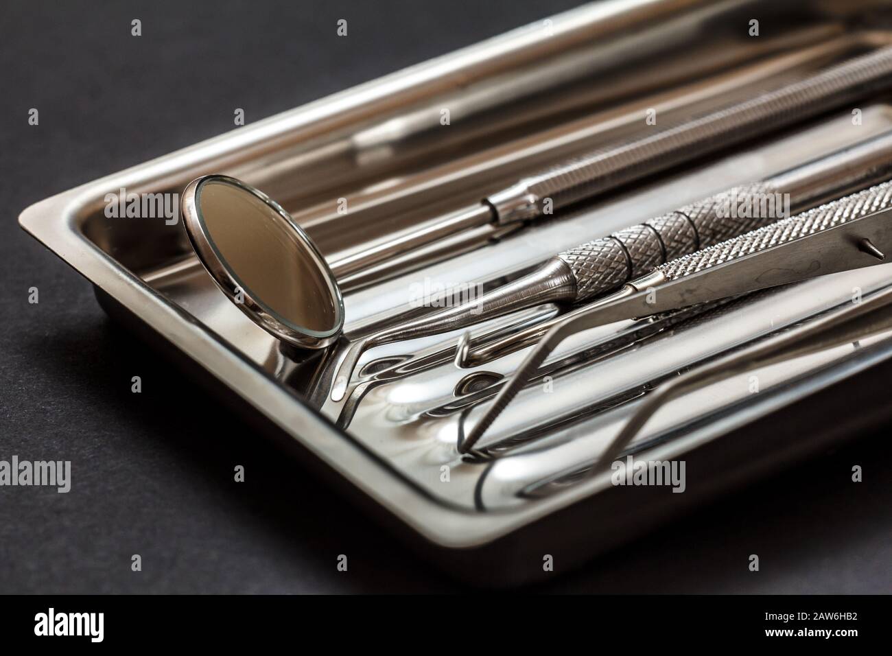 Close-up view of composite filling instruments for dental treatment. Medical tools in stainless steel tray on black background. Shallow depth of field Stock Photo