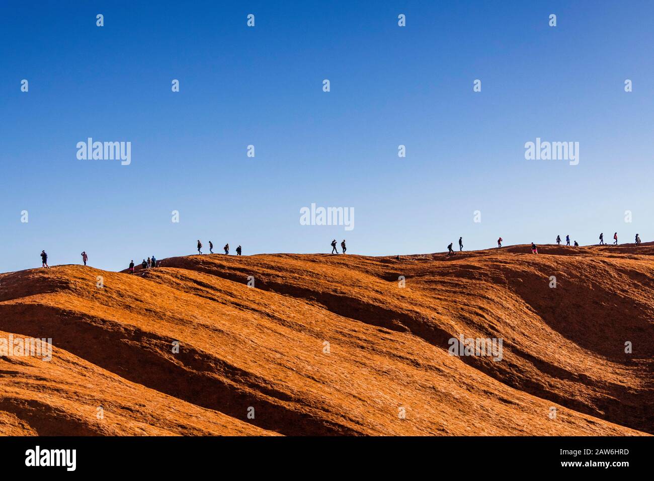 A line of tourists make the final trek along the top of Uluru in the final month prior to it being closed to climbers. Stock Photo