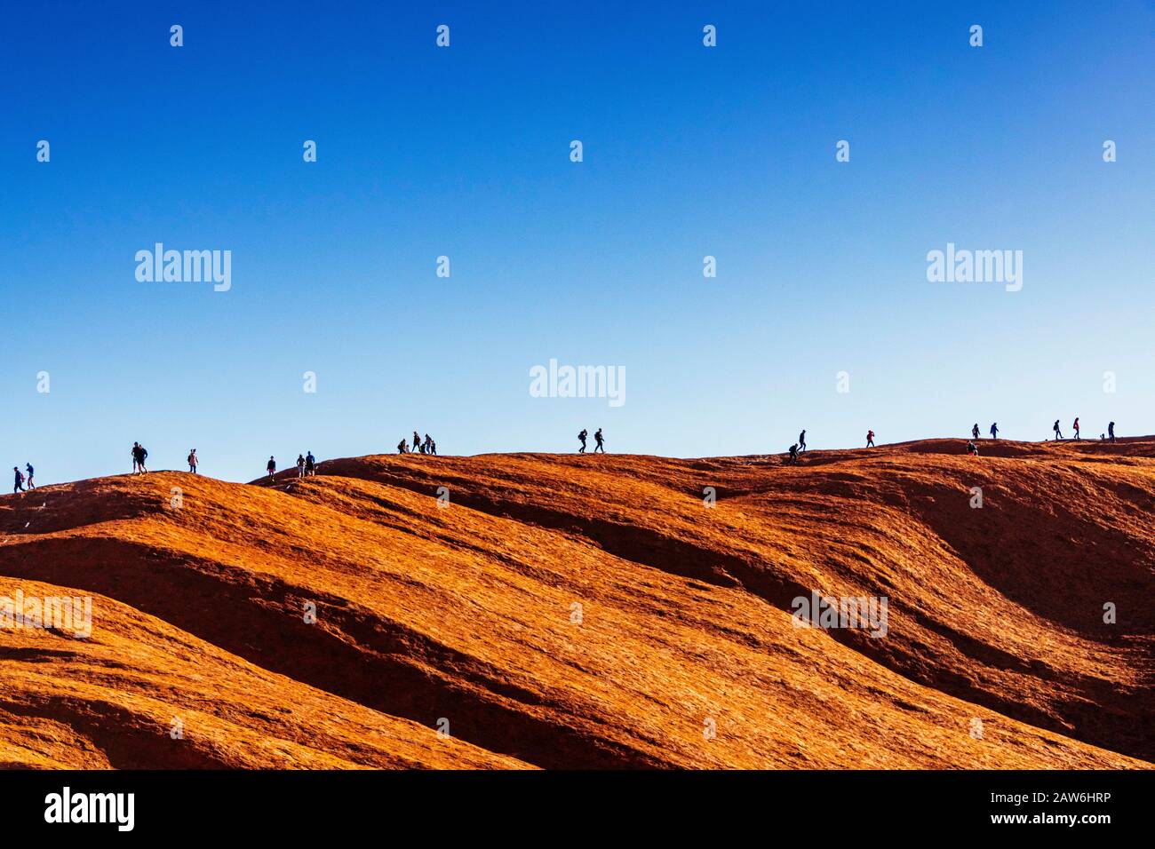 A line of tourists make the final trek along the top of Uluru in the final month prior to it being closed to climbers. Stock Photo