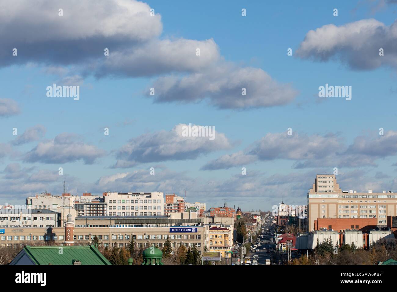 blue sky with clouds over roofs of city illuminated by day sun, Russia, Omsk, 30.10.2019. Stock Photo