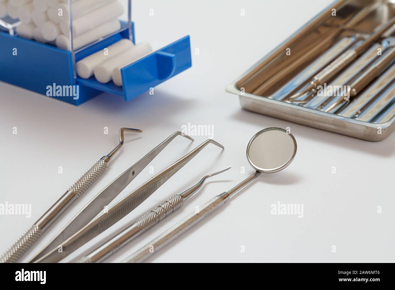 Set of metal dental instruments for dental treatment on white background. Medical tools, stainless steel tray and cotton tampons holder. Close-up view Stock Photo
