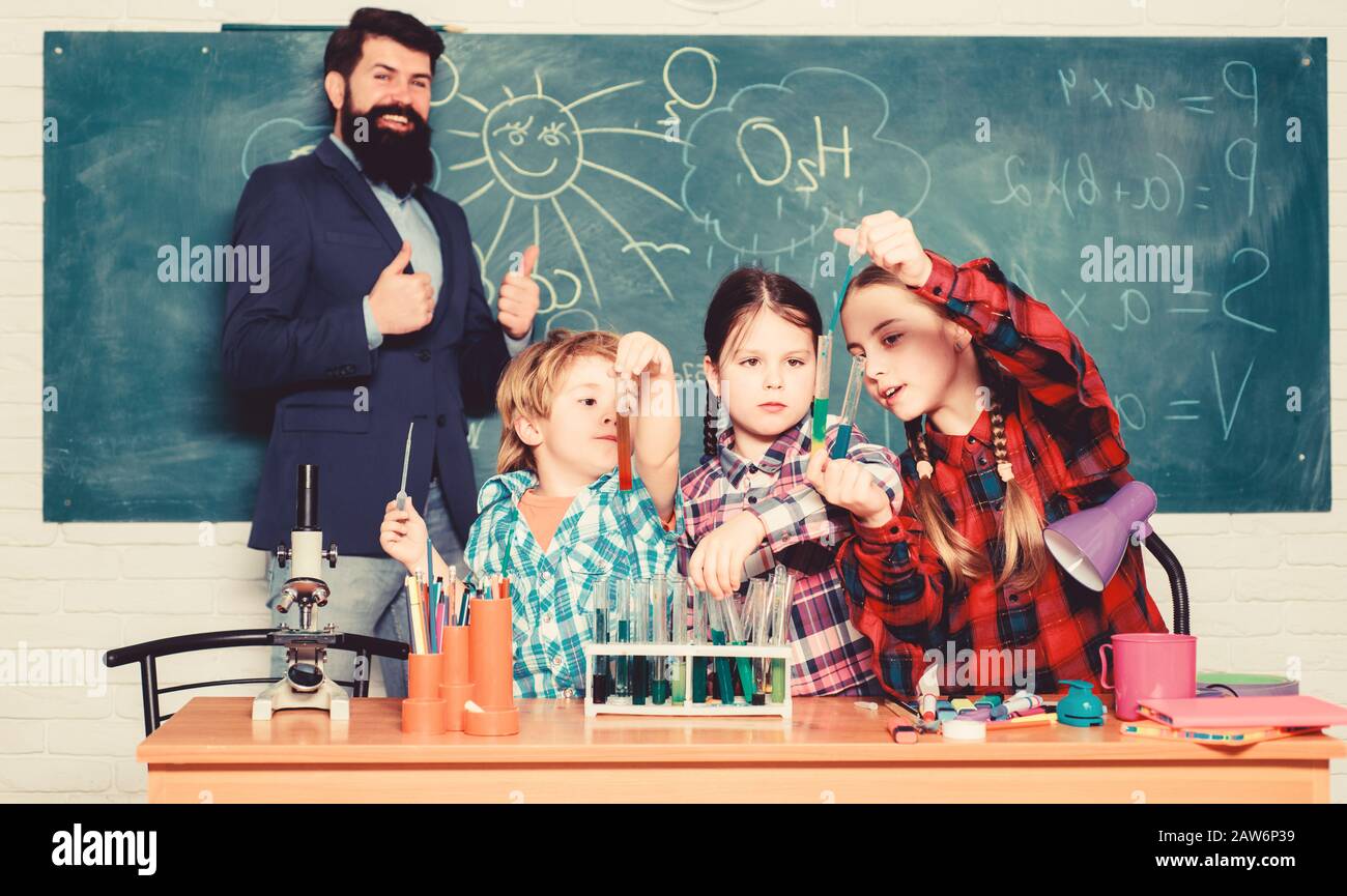 Little kids learning chemistry in school laboratory. school kids scientist studying science. happy children teacher. back to school. students doing science experiments with microscope in lab. team. Stock Photo