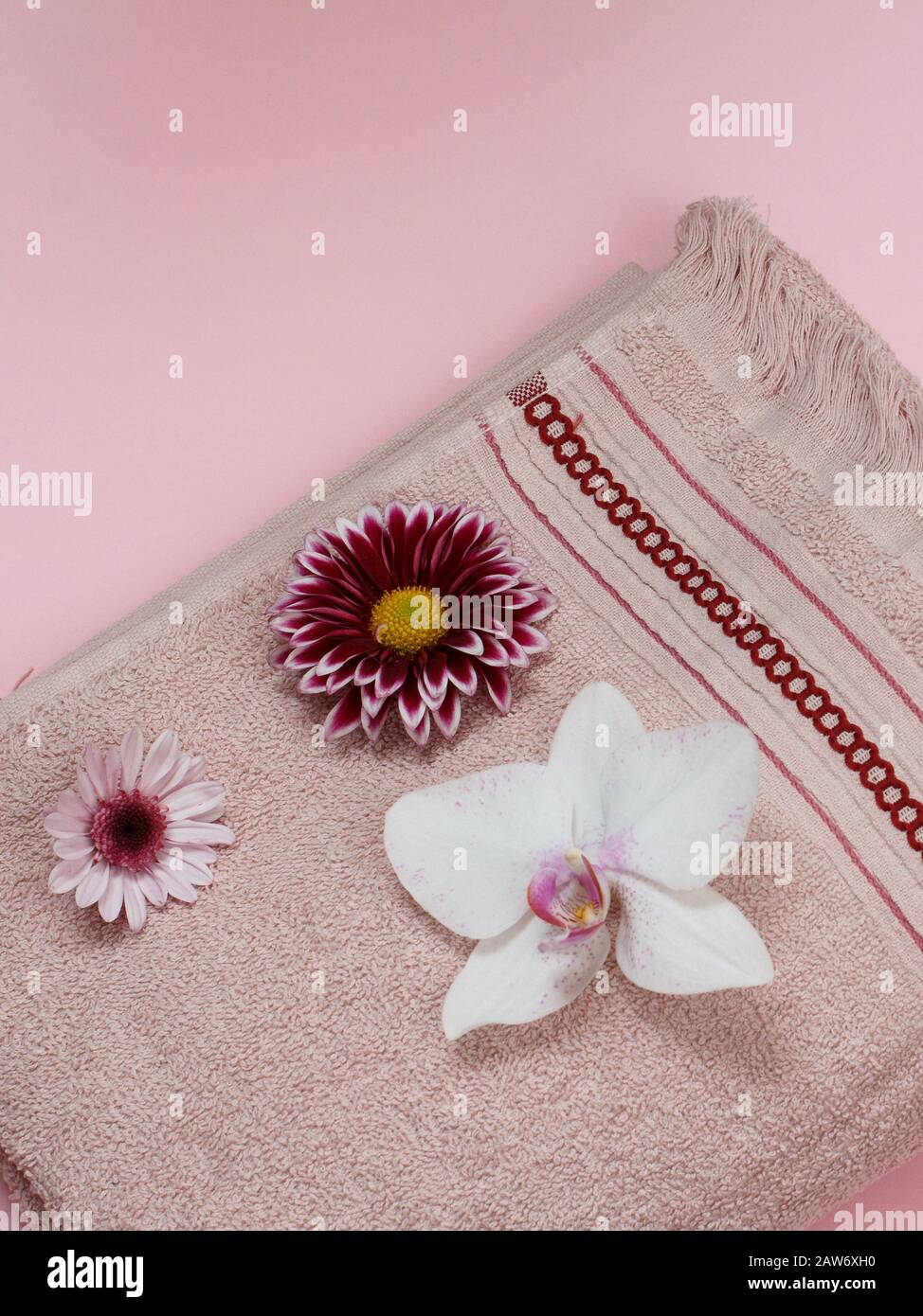 Soft terry towel with white orchid and flower buds on pink background. Top view. Stock Photo